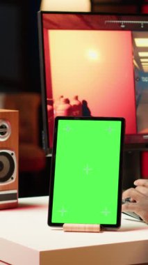 Çevrimiçi çok oyunculu video oyununda yarışan profesyonel streamer 'ın yanında dikey video yeşil ekranlı tablet, evde canlı yayınlanıyor. Chroma anahtar aygıtı ve bilgisayarda oynayan adam, konuşmak için kulaklık kullanıyor