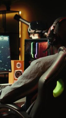 Dikey video adam kulaklık takıyor, oyun oynuyor abonelere profesyonel esport becerileri öğretiyor, yakın çekim yapıyor. Medya yıldızı, izleyicilerle sohbet etmek için kulaklık mikrofonu kullanıyor, oyun dersi, kamera B