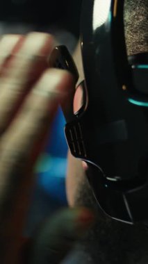 Bilgisayarda SF video oyunu oynayan Dikey Video Adam, neon ışıklı dairede eğleniyor, kapatın. Oyuncu online çok oyunculu oyunda, takım arkadaşları kamera B ile konuşmak için kulaklık kullanıyor