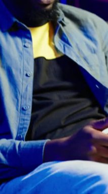 Evde video oyunu oynamak için kulaklık ve kumanda kullanarak kanepede oturan dikey video oynatıcı, kapat. Ev sinemasındaki adam yüksek teknoloji oyun konsolu oyun sahasını kullanarak rakiplerini yeniyor, kamera A