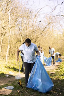 Ormanda çöp toplayan bir kadın eylemci, çöpleri ve plastik atıkları temizliyor. Afrikalı Amerikalı gönüllü olarak yasadışı çöplüğe karşı çalışıyor..