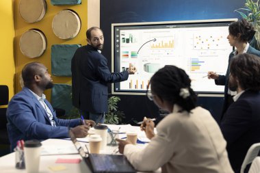 İş ortaklarından oluşan bir ekip, yürütme toplantısında gelirleri artırmanın yollarını tartışıyor, istatistikleri analiz ederek projeyi sonlandırıyor. Girişim çalışanları hedeflere ulaşmak için işbirliği yapıyor.