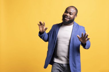 Stüdyonun arka planında izole edilmiş kendine güvenen Afro-Amerikan bir adamın portresi. Dertsiz tasasız BIPOC 'lu şık görünüşlü, umursamaz ve gülümseyen biri.
