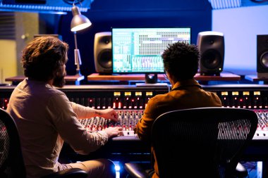Sanatçı ve besteci birlikte müzik stüdyosunda çalışıyor, kontrol odasında hit bir şarkı üzerinde çalışıyorlar. Teknisyen melodileri ses konsolu ve faders veya düğmeler ile karıştırır, kayıtları düzenler.