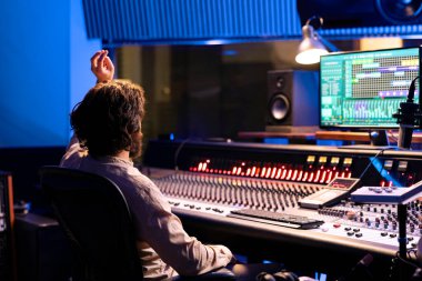 Ses tasarımcısı ses kabinindeki şarkıcının kayıt seansına başlaması için geri sayım yapıyor, kontrol odasında yeni müzik üretiyor. Yetenekli ses mühendisi işletim paneli.