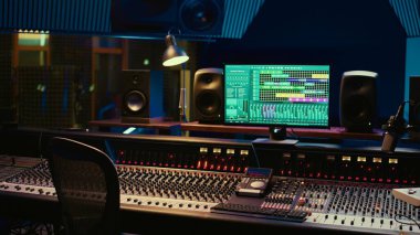 Ses parçalarını karıştırmak ve ustalaştırmak için kullanılan daw yazılımıyla müzik kayıt stüdyosu kontrol odası, ses geçirmez boş profesyonel alan. Ses dalgalarını düzenlemek için kontrol panelindeki modern kaydırıcılar.