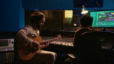 Performans yazarı elektro akustik gitarıyla yeni şarkılar söylüyor ve prodüksiyon sonrası yeni şarkılar kaydediyor. Stüdyoda ses mühendisiyle işbirliği içinde çalışan bir müzisyen. Kamera A.