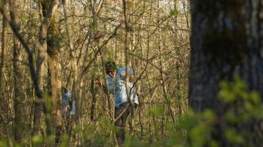Bir grup gönüllü kayıp bir kişiyi arıyor, ormanda isimlerini haykırıyor ve adımları takip etmek için ağaçların arasından geçiyor. Arama ekibi kayıp bir kurbanı arıyor. Kamera A.