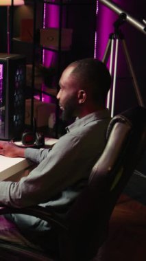 Dikey Video Adam bilgisayar masasında bilgisayar oyunu oynayarak eğleniyor, işten izin gününün tadını çıkarıyor. Oyuncu evindeki konforlu kamerayla online çok oyunculu atıcılarla savaşıyor.