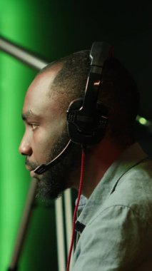 Oyun odasında kulaklık takan, bilgisayarda video oyunu oynayan dikey video oyunu oyuncusu. Gecenin geç saatlerinde oyun turnuvasında oynayan neşeli esport oyuncularını kapatın.