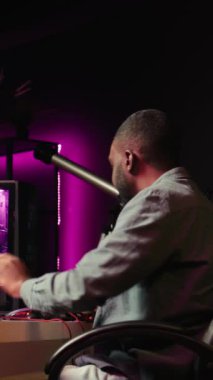 Dikey video gülen oyuncu kulaklıkla oyun odasında dinleniyor, güçlü bilgisayarlarda video oyunları oynuyor, arkadaşlarıyla sohbet ediyor. Neşeli esport oyuncusu oyun turnuvasında oynuyor, kamera