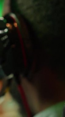 Evde video oyunu oynarken kulaklık takan Dikey Video Adam kendini daha iyi daldırmak için. Çevrimiçi çoklu oyunculu esport turnuvasına katılan oyuncuya yakın çekim, yenmek için mücadele