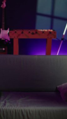 Dikey Videocu eve geliyor, oyun oynuyor ve eğleniyor. Neon ışıklı oturma odasında koltukta oturan adam, konsolda video oyunu oynuyor, yoğun bir iş gününden sonra dinleniyor, kamera B