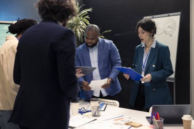 İş ortakları son bütçe planlarını gözden geçiriyorlar, gelişmeleri güvence altına almak için güncellemeler ve ayrıntıları paylaşmak üzere bir brifing toplantısı düzenliyorlar. Bir proje için karar veren meslektaşlar.