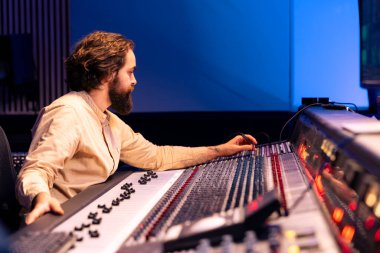 Mühendis faders ve kontrol masası düğmelerini karıştırarak ses kalitesini arttırıyor, yeni albüm üzerinde çalışıyor. Şarkıları dengeleyen ve efekt ekleyen teknik uzman, stereo dişli.