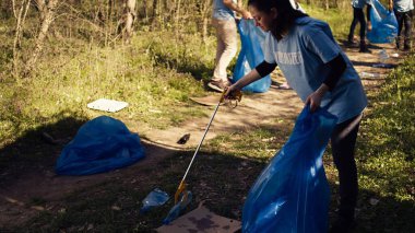 Çevreci aktivist bir pençe aleti ve geri dönüşümle çöpleri topluyor, doğal orman ortamını koruyor ve çöp temizliyor. Kadın kirliliği durdurmak için gönüllü çalışıyor. Kamera B.