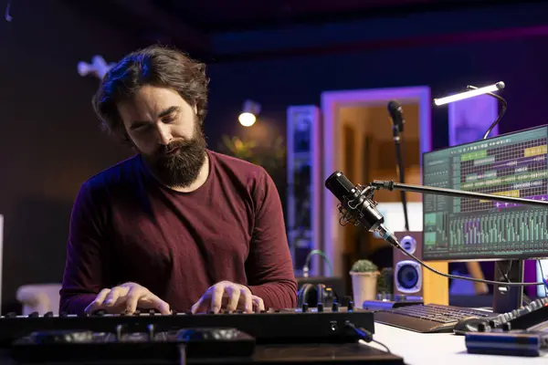 stock image Audio engineer playing electronic keyboard and recording tunes, using mixing console and midi controller to create new music. Artist songwriter uses stereo tools and synthesizer at home studio.