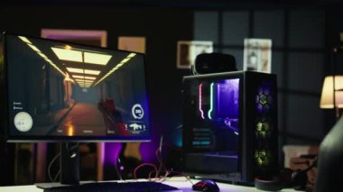 Masada kulaklıklar ve yüksek teknoloji VR kulaklığın yanında RGB 'nin yaktığı bilgisayarlı boş neon ışıklı oturma odası görüntüsü. Dairedeki bilgisayar çevresi ve bilgisayar ekranlarında açık bırakılan FPS video oyunu