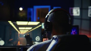 Oyuncuların online çok oyunculu video oyununda, kulaklık mikrofonuyla yarışarak eğlenmelerine yakın çekim yapın. Oyun oynarken gülen adam, arkadaşlarıyla kulaklıkla konuşan mikrofon, kamera B