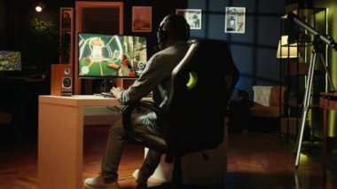Kulaklıklı neşeli bir oyuncu oyun odasında eğleniyor, bilgisayarda video oyunları oynuyor. Neşeli esport oyuncularının kapanışı oyun turnuvasında gece geç saatlerde, kamera B
