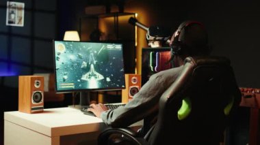 Kulaklık takan, oyun oynayan, abonelere profesyonel esport becerileri öğreten, yakın çekim yapan bir adam. Medya yıldızı, izleyicilerle sohbet etmek için kulaklık mikrofonu kullanıyor, oyun dersi, kamera B