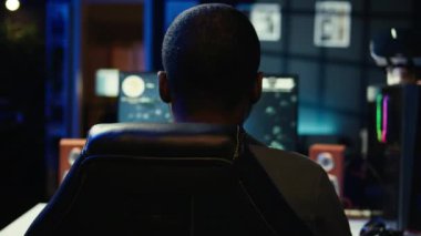 SF video oyunu oynayan bir adam neon ışıklı apartman odasında. Oyuncu, RGB 'de bilgisayar ekranında uzay gemisi uçurma oyununun keyfini çıkarırken, gece geç saatlerde evi aydınlattı, kamera B de çekim yaptı.