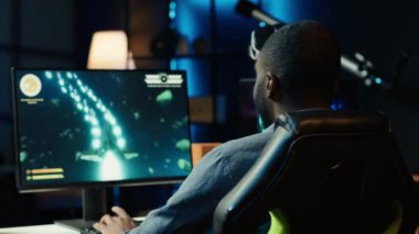 Neon ışıklı apartmandaki Afrikalı Amerikalı oyuncu video oyunu müsabakası sırasında bilgisayar ekranına çok dikkat ediyor. İnternet Esport Turnuvası 'nda yarışan kişi, Kamera A