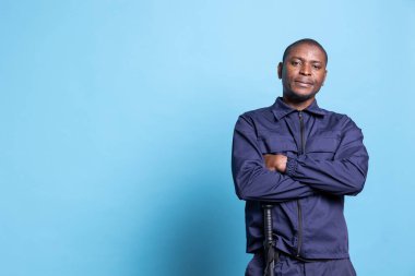 Kamera karşısında kollarını kavuşturarak poz veren gururlu bir güvenlik görevlisinin portresi. Devriye üniforması içinde özgüven ve özveri ile. Eğitimli silahlı koruma koruma koruma ve güvenlik üzerine çalışır..