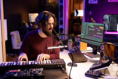 Yaratıcı müzisyen mikrofon ve Midi kontrolörüyle yeni melodiler kaydediyor. Ev stüdyosunda piyano tuşları çalıyor. Modern elektronik klavye ve ses donanımı ile müzik üreten yetenekli bir besteci.