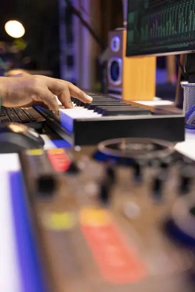 stock image Artist composer playing a track on midi controller in home studio, adding piano notes on an old audio recording. Sound engineer producing modern tracks on stereo console. Close up.