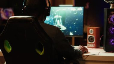 Oyuncu arkadaşlarıyla online çok oyunculu uzay gemisi video oyunu oynuyor, karanlık odada dinleniyor. Oyuncu takım arkadaşlarıyla konuşuyor, uçan uzay aracı, neon ışıklarda eğleniyor apartman süslemesi, kamera A