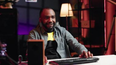 Neşeli oyuncular canlı oturma odasından neon ışıklarla yoğun internet çok oyunculu video oyununda yarışıyorlar. Gülümseyen Afro-Amerikan adam, bilgisayar kullanıyor, oyun sırasında dalgın deneyimi var, kamera A