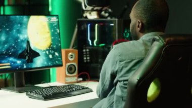 Bilgisayar monitöründe SF nişancı video oyunu oynayan, arkadaşlarıyla kulaklığa konuşan bir adam. Oyuncu, Esports takımı kamera A ile sohbet etmek için uzay gemisiyle eğlenirken kulaklık kullanıyor.