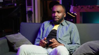 Oyuncu, konsol sisteminde kumanda kullanarak bilgisayar oyunu oynarken kaybettikten sonra üzüldü. Adam mağlup olduktan sonra hayal kırıklığına uğruyor. Oyun sahası, kamera A ile oyun oynuyor.