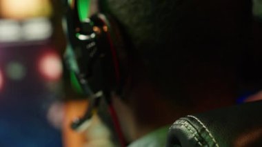 Evde video oyunu oynarken kulaklık takan adam kendini daha iyi daldırmak için. Çevrimiçi çoklu oyunculu esport turnuvasına katılan oyuncuya yakın çekim, düşmanları yenmek için mücadele, kamera A