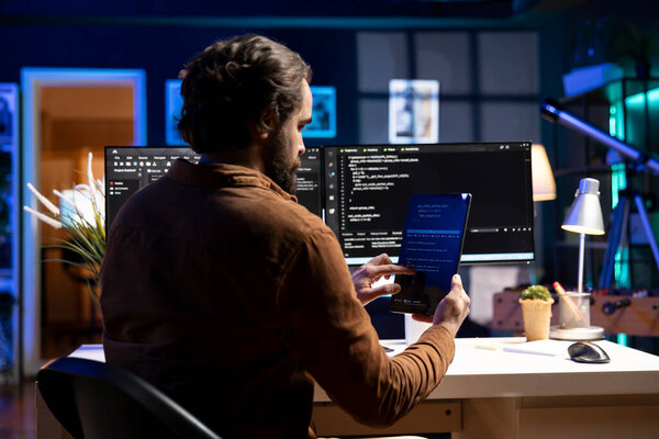 Programmer using tablet to fix vulnerabilities in software enabling attackers to compromise systems. Man taking care of security exposures in operating system, writing code on device
