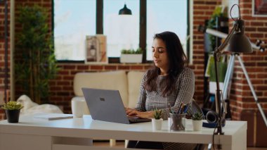 Serbest çalışan kadın bilgisayar masasında oturuyor, kişisel ofiste dizüstü bilgisayarda klavye kullanıyor. Serbest çalışan iş kadını not defterine veri giriyor, son teslim tarihinden önce işini yapıyor.