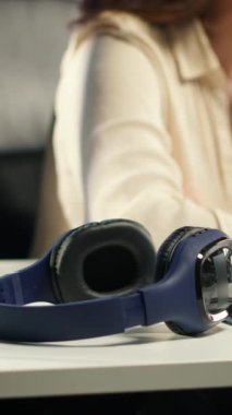 Dikey Videolu Güçlü Kadın Lider, akıllı bir ofiste üretkenlik için kulaklıklarını alıyor, kurumsal sonuçlara ulaşmak için etkili bir iletişim için sesli kitap ve ağ dinliyor.