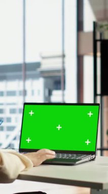 Dikey Video Genç iş girişimcisi aletlerinin yeşil ekran modeline bakıyor, modern şehir kurumsal ofisinde çalışıyor. Kadın lider başarı için finansmanı arttıracak bir strateji geliştiriyor.
