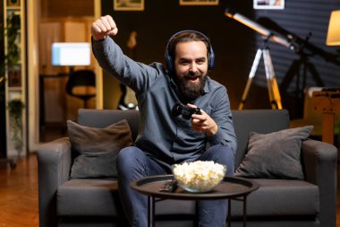 Oyuncu, video oyunu seviyesini kazandıktan sonra rahatlamış hissediyor, heyecanla televizyona bağırıyor. Oyun konsolunda oynarken zaferi gördükten sonra sevinçten bağıran mutlu bir adam.