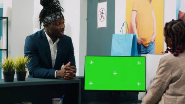 Afrikalı Amerikalı çalışanlar kasada yeşil ekran ile çalışıyor, kasada müşteriye kıyafet siparişi hazırlıyorlar. İzole edilmiş kromakey ekranlı bilgisayar kullanan perakende işçisi. Kamera A.