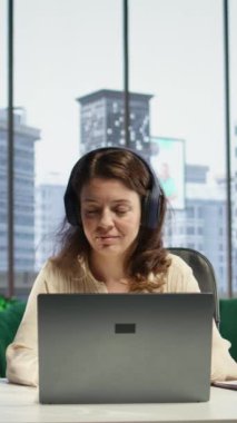 Dikey Video Dünyası girişimcisi kulaklığında müzik eşliğinde çalışmaktan ve kurumsal ofisindeki günlük görevleri çözmekten hoşlanıyor. Kararlı kadın CEO favori şarkılar ve verimlilikle eğleniyor