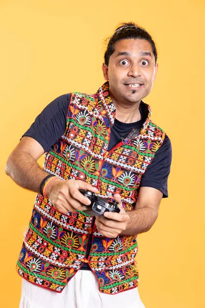 stock image Portrait of joyous man being entertained by videogames, using controller, studio background. Jolly gamer having fun by participating in online multiplayer game using console system