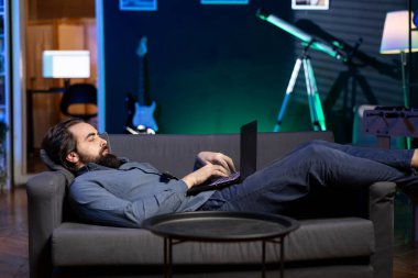 Freelancer evdeki kanepeye uzanıp laptoptaki iş ile ilgili işleri hallediyordu. Uzaktan kumandalı çalışan, neon ışıklı oturma odasında uzanıp not defterine e-postalar gönderiyor.