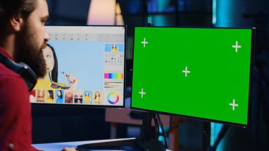 Fotoğraf editörü, fotoğraf stüdyosunda moda dergisi için profesyonel kamerayla çekilen editör resimlerine bakmak için yeşil ekran monitörü kullanıyor. Freelancer, medya ajansındaki görüntülere göz atıyor