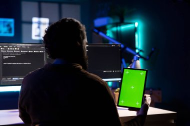 Siber güvenlik uzmanı güvenlik açıklarını ve virüslü yazılımları bulmak için izole ekran tableti kullanıyor. Programcı siber saldırıları önlemek için taşınabilir cihaza güçlendirilmiş kod yüklüyor