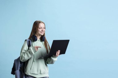 Neşeli genç, video konferans sırasında arkadaşlarıyla bilgisayar ve stüdyo geçmişi kullanarak dostça sohbet ediyor. Çevrimiçi video görüşmesi sırasında arkadaşlarıyla arayı kapatırken gülümseyen kişi