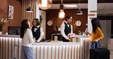 Çalışan ekibi, beş yıldızlı otelde iki kadını karşılayarak giriş yaptıktan sonra bavul taşımaya yardım eden konsiyerj hizmetleri sunuyor. Tatilde seyahat eden kız arkadaşlar, hoş geldiniz turistleri..