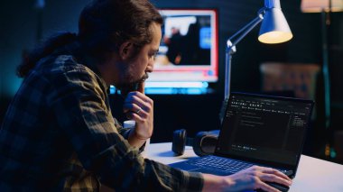 Deneyimli programcı Java programlama dillerini kullanarak daire ofisindeyken laptop ekranına kod yazar. Geliştirici evden ve kamera A 'dan çalışırken veritabanı hatalarını düzeltmeye çalışıyor