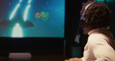 Oyuncu, ultra-geniş akıllı TV 'de bilim-kurgu uçuş oyunu oynuyor, takım arkadaşlarıyla kulaklık kullanarak iletişim kuruyor. Oyuncu SF video oyununda son göreve ulaşıyor.